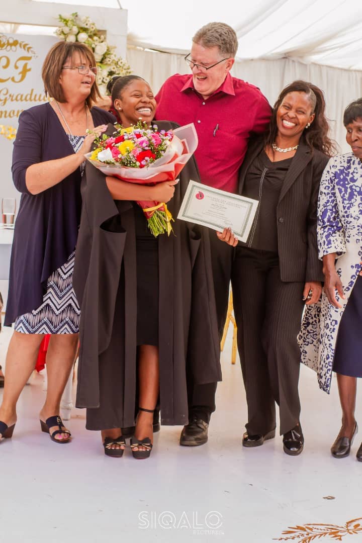 A Victory Learning Centre graduate celebrating with her certificate and flowers at the graduation ceremony